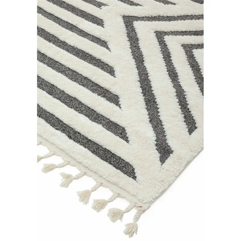 Cream and grey geometric pattern rug with tasselled edge, close-up of corner detail