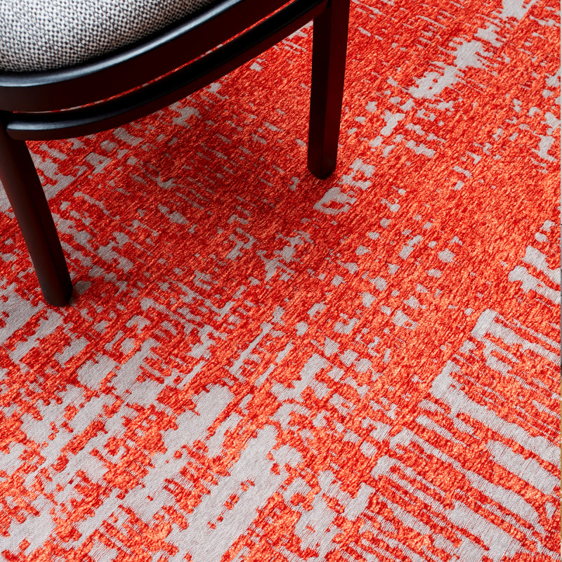 Red patterned area rug with modern abstract design and chair leg visible