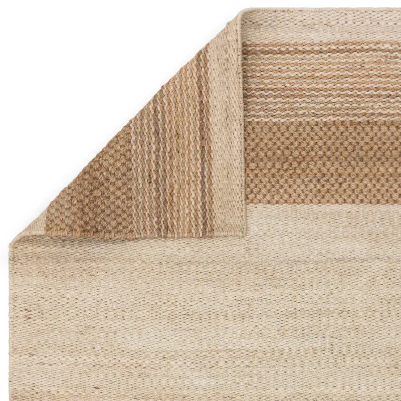 Jute area rug with natural beige and brown woven texture, corner folded to show thickness