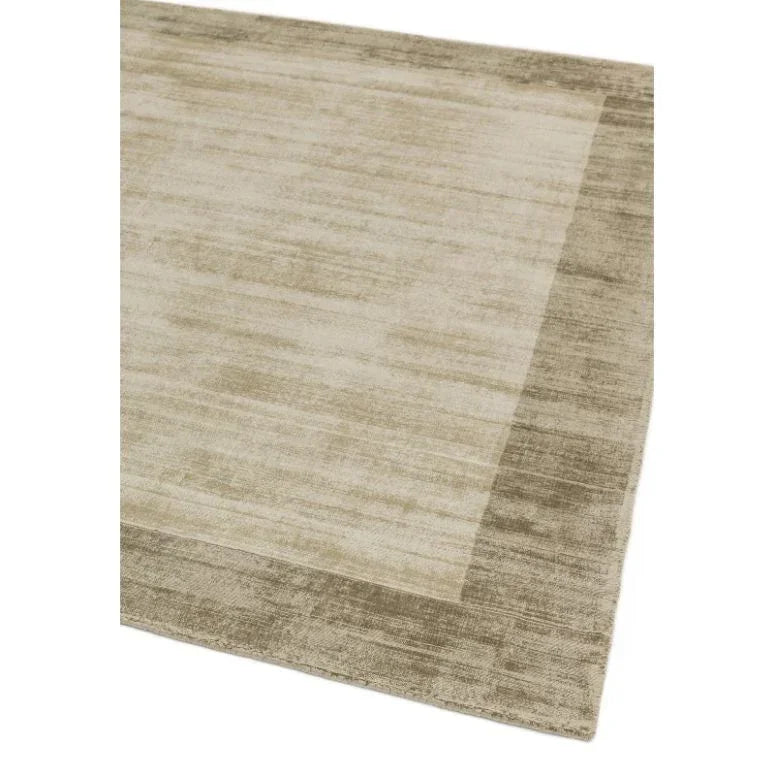 Beige bordered area rug with subtle textured pattern, corner view