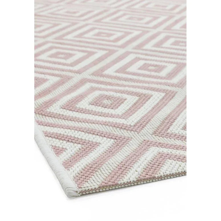 Pink and white geometric rug with textured diamond pattern, close-up corner view