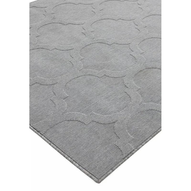 Grey patterned rug with textured geometric design and finished edge, corner angle view