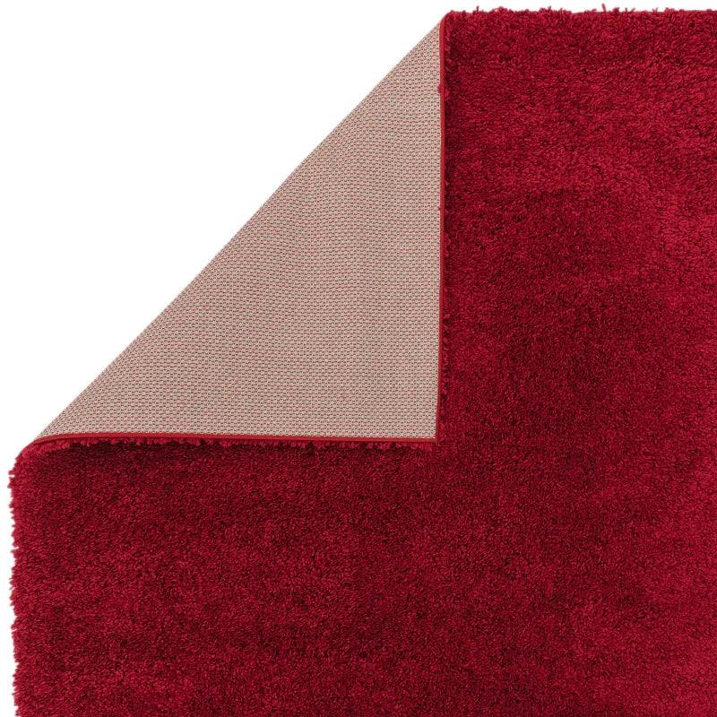 Red shaggy rug corner flipped to show non-slip backing detail