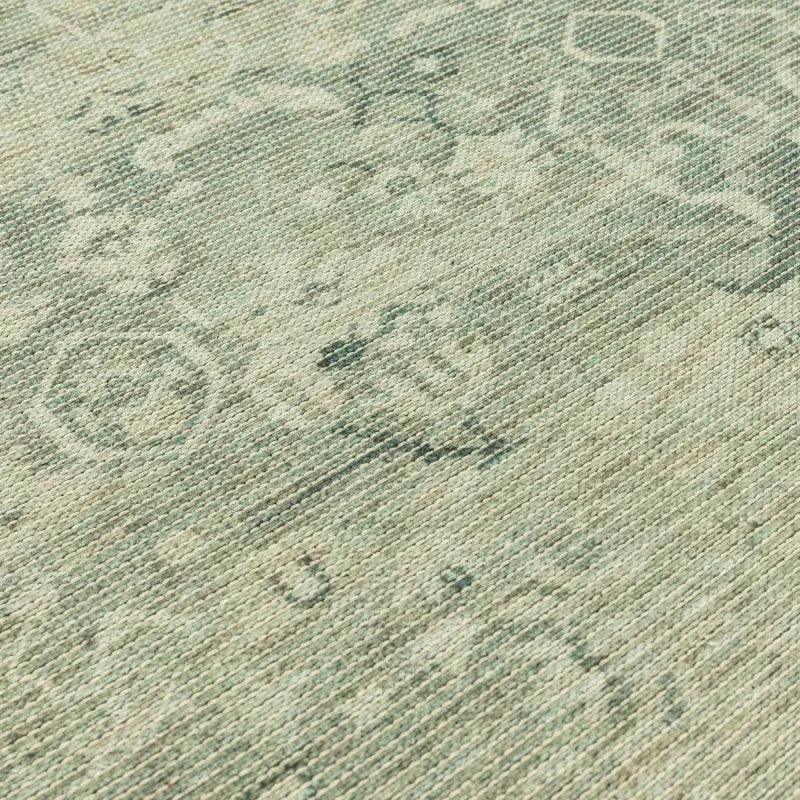 Closeup of woven rug with subtle green and beige pattern texture