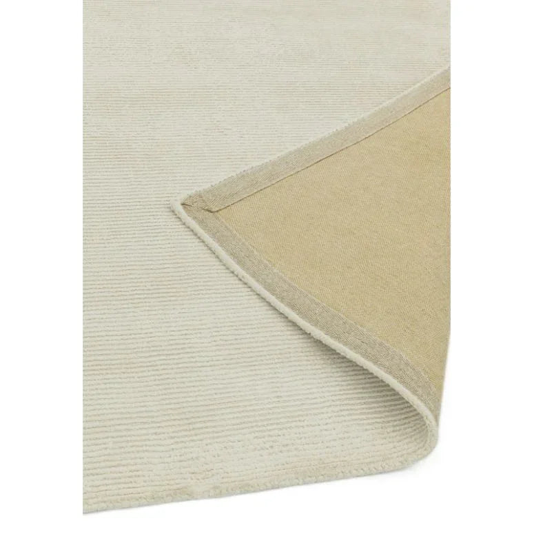 Textured cream rug with visible backing and corner folded over, close-up view