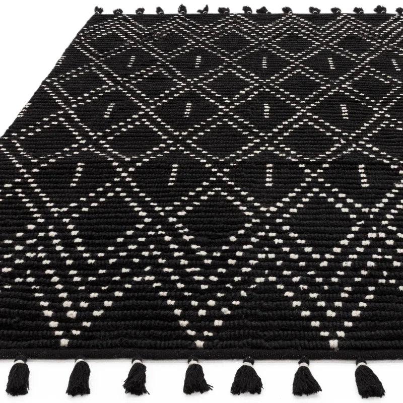 Black patterned rug with white diamond design and tasselled edge, close-up view