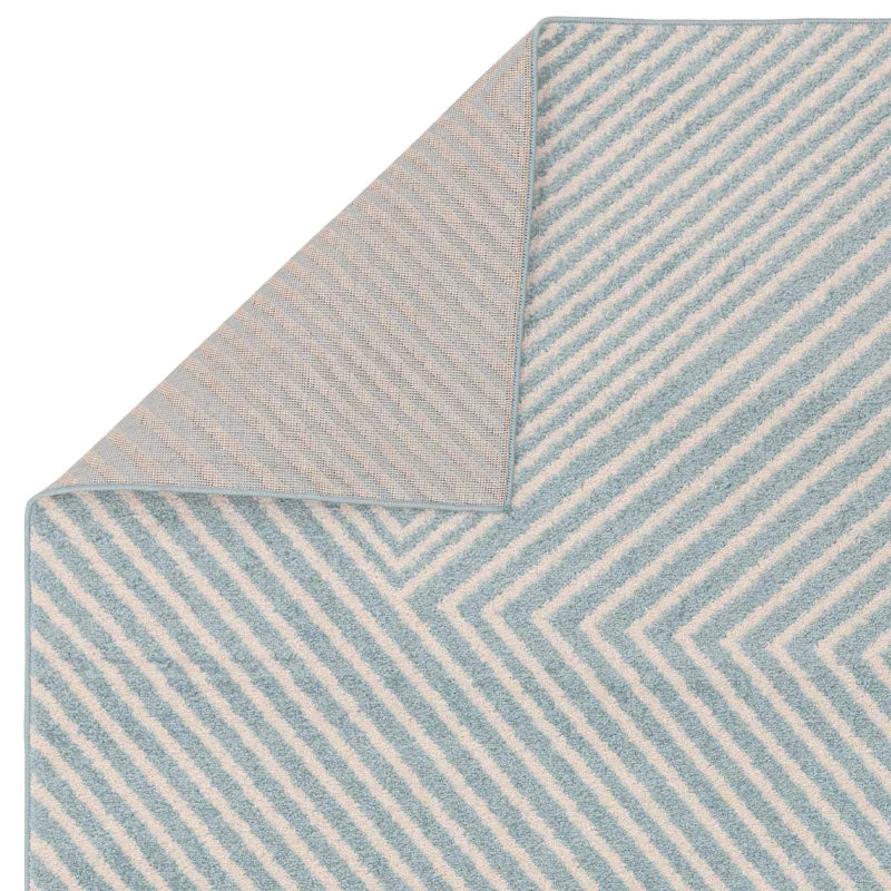 Blue and white geometric area rug with corner flipped to show backing