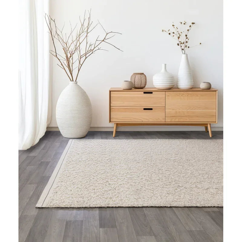 Light wood sideboard with vases and beige rug on grey laminate floor in modern living room