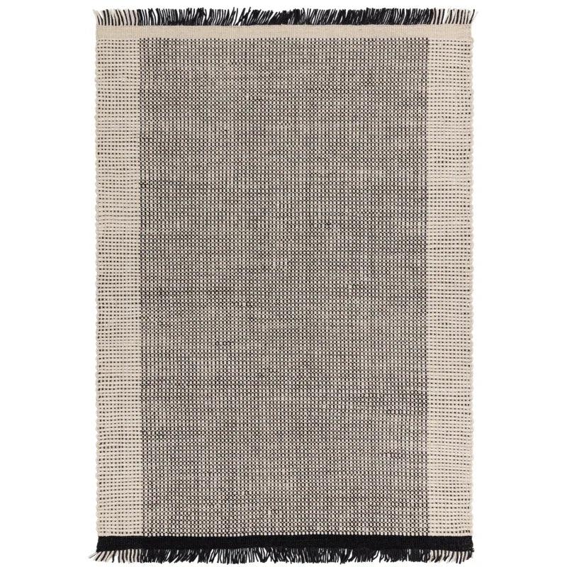 Rectangular woven rug with black and beige pattern and fringed edges