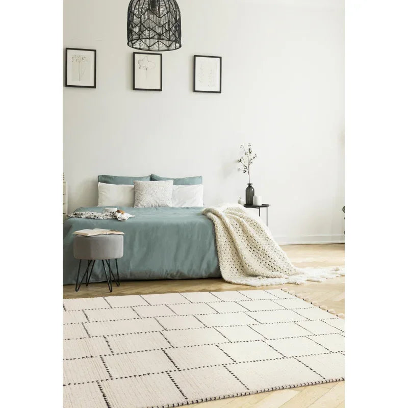 Modern bedroom with blue bed, patterned area rug, and decorative throw blanket