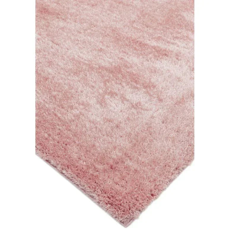 Corner view of pink shaggy area rug with soft, plush pile texture