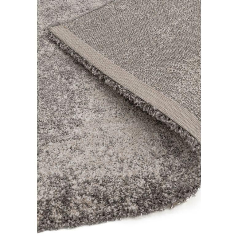 Grey shaggy rug with soft pile and woven backing, corner folded to show texture
