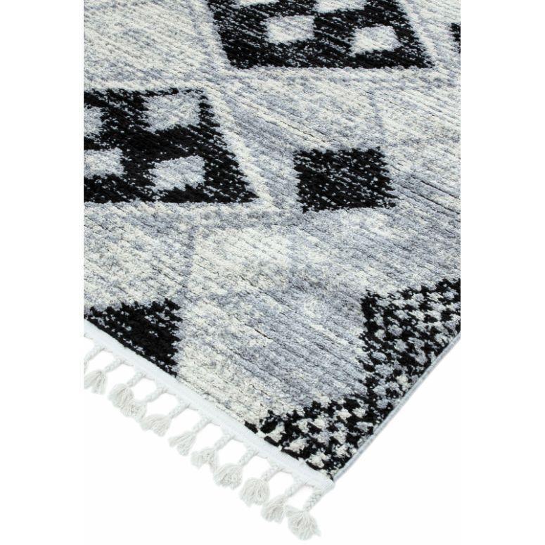 Grey rug with black geometric pattern and tassel fringe corner detail