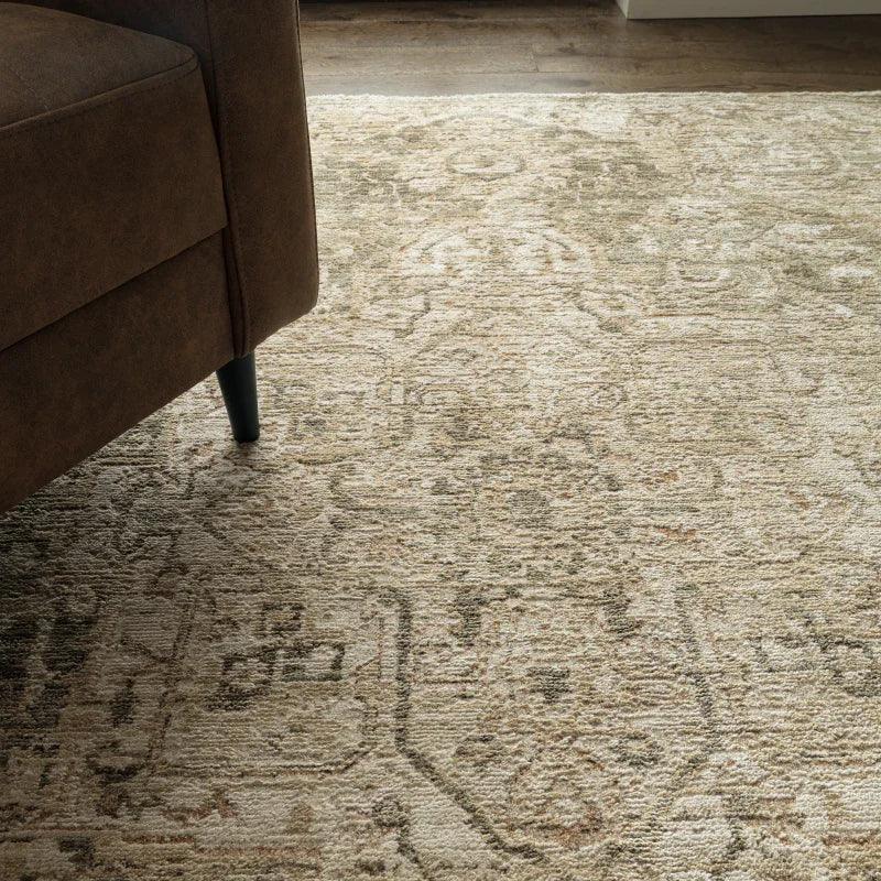 Beige patterned area rug beside brown fabric sofa on hardwood floor