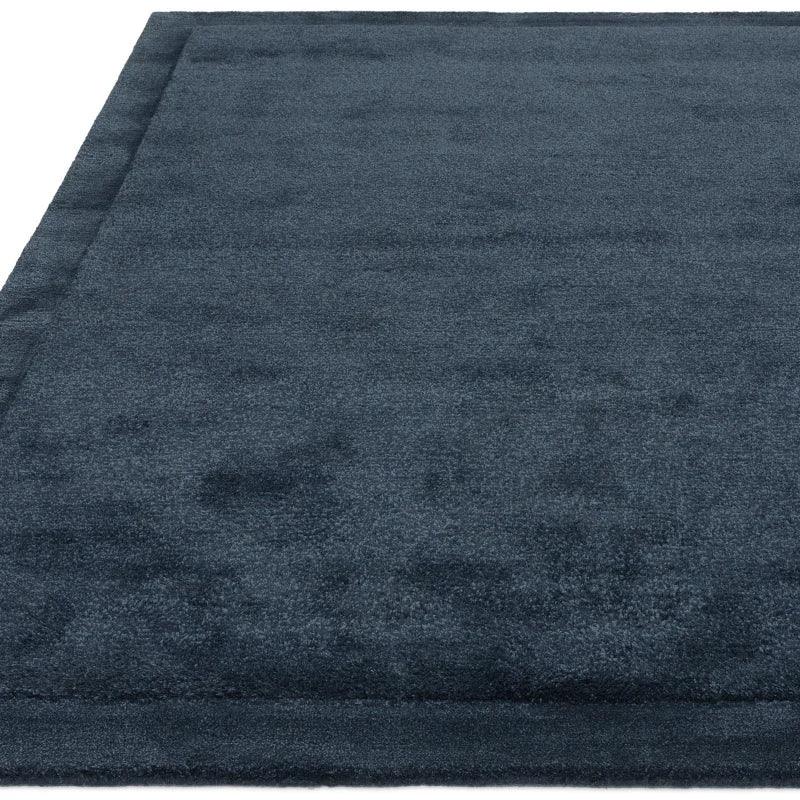 Navy blue area rug with soft texture and subtle border detail, close-up angle