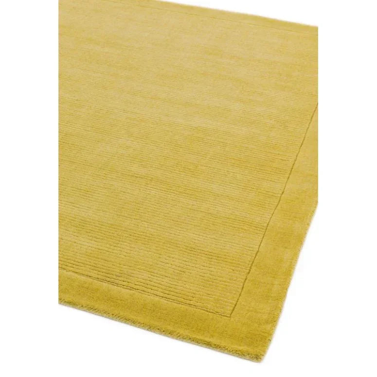 Yellow area rug with subtle textured border and soft pile, angled corner view