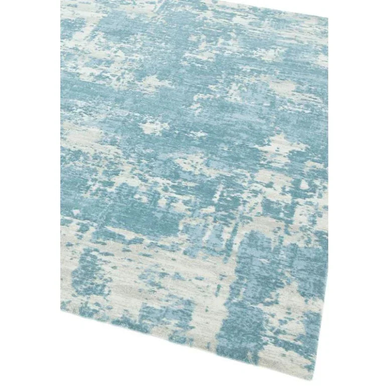 Blue and cream abstract area rug with textured pattern, corner view on white background