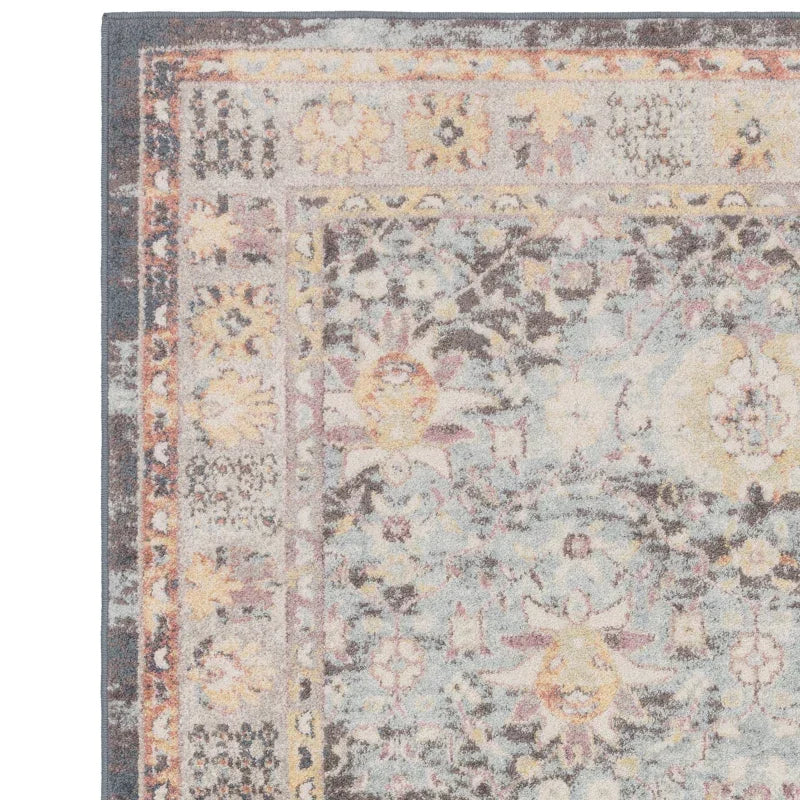 Pastel floral area rug corner with intricate faded pattern and decorative border