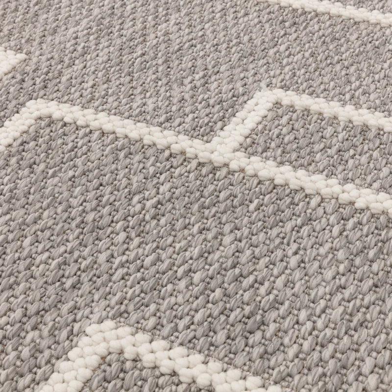 Grey woven rug with white geometric pattern and textured surface, close-up view
