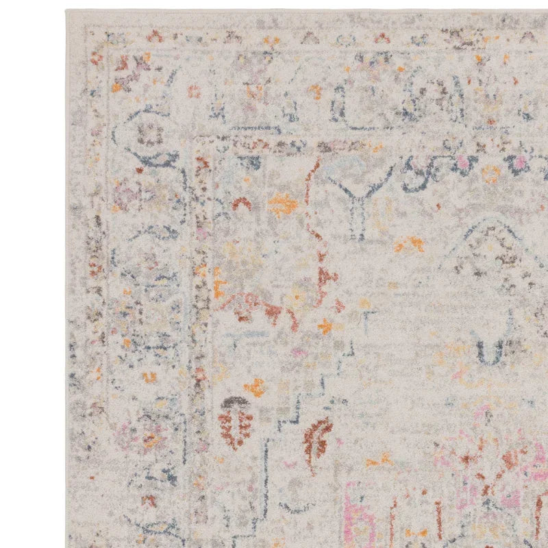 Corner detail of cream patterned area rug with faded multicolour accents and textured weave