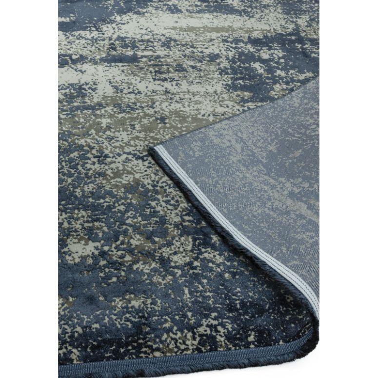 Blue and grey abstract area rug with folded corner showing backing detail