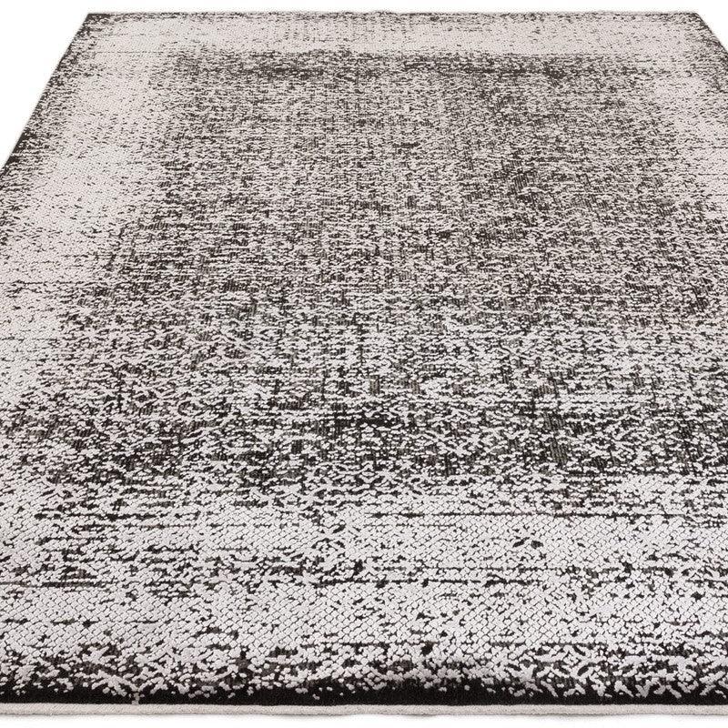 Black and white distressed area rug with textured pattern, shown from a low angle