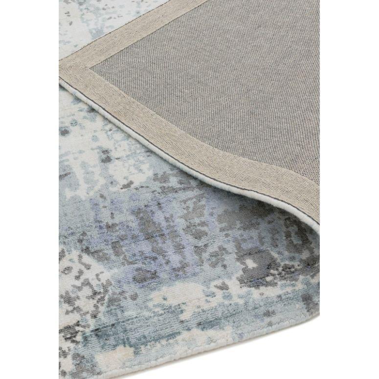 Blue and grey abstract patterned rug with corner flipped to show backing