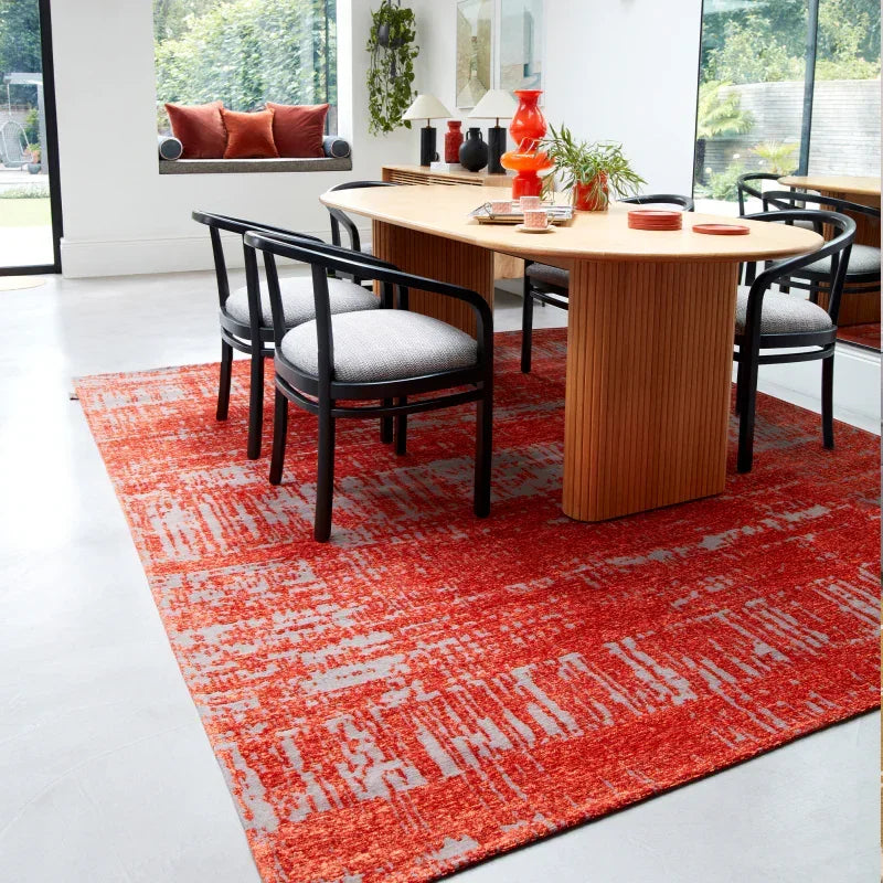Contemporary dining table set with black chairs on orange patterned rug in modern room