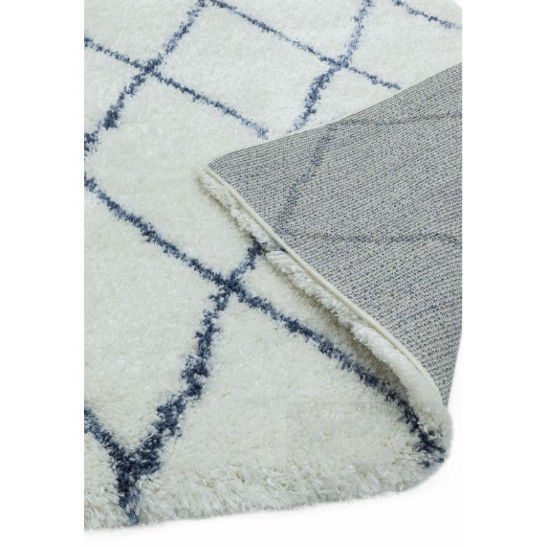 White shaggy rug with navy geometric pattern, corner flipped to show backing