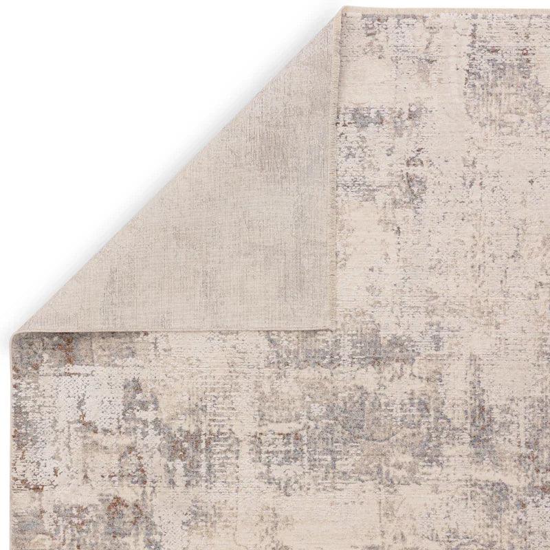 Beige patterned area rug with one corner folded to show backing texture