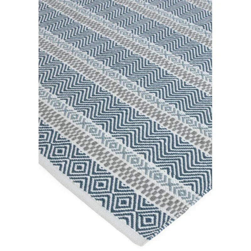 Blue and grey patterned rug with zigzag and diamond geometric design, corner close-up view