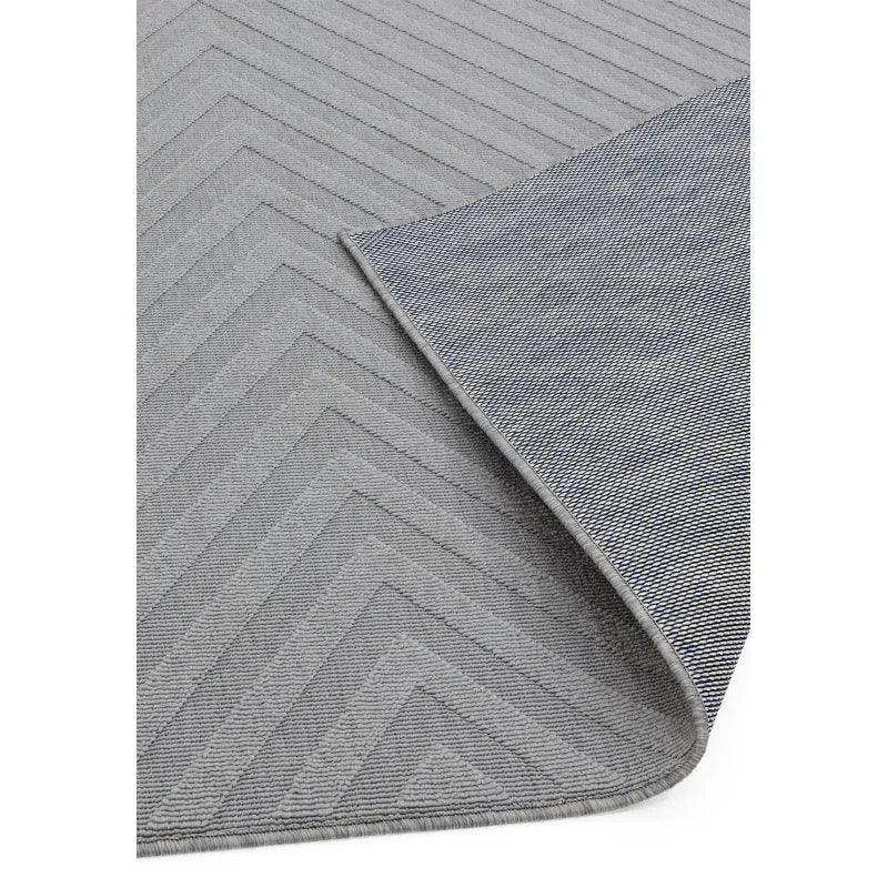Grey chevron pattern rug with corner flipped to show backing detail