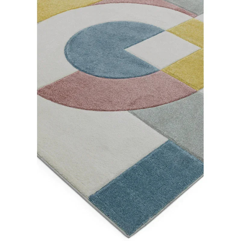 Geometric area rug with blue, pink, yellow and grey shapes on a cream background