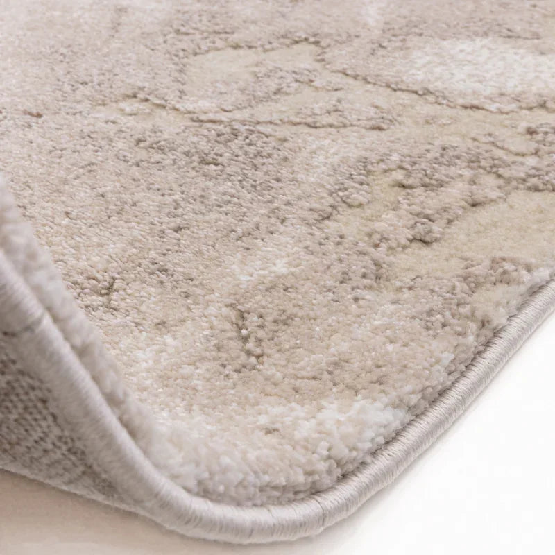 Close-up of beige patterned rug with soft pile and finished edge