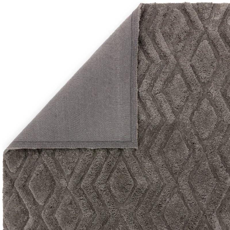 Grey geometric pattern rug with textured diamond design and corner folded to show backing
