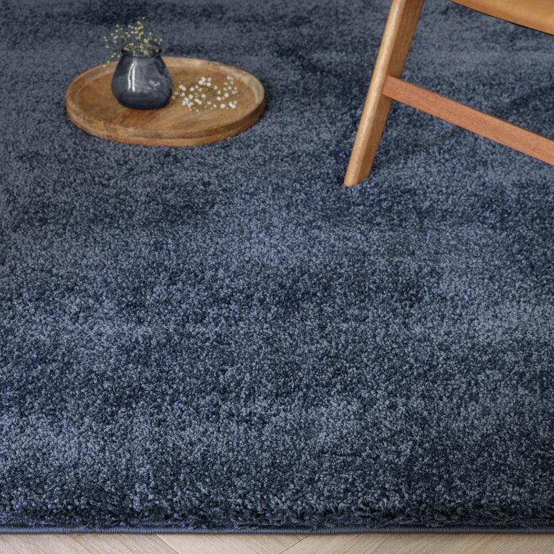 Dark grey shaggy rug with wooden chair and tray on light wood floor