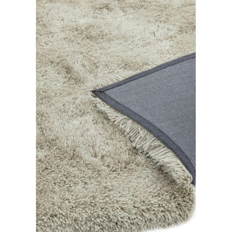 Beige shaggy rug closeup with visible soft pile and flipped corner showing backing
