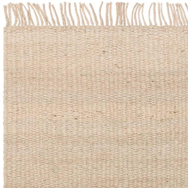 Beige woven jute rug corner with textured pattern and fringe edging