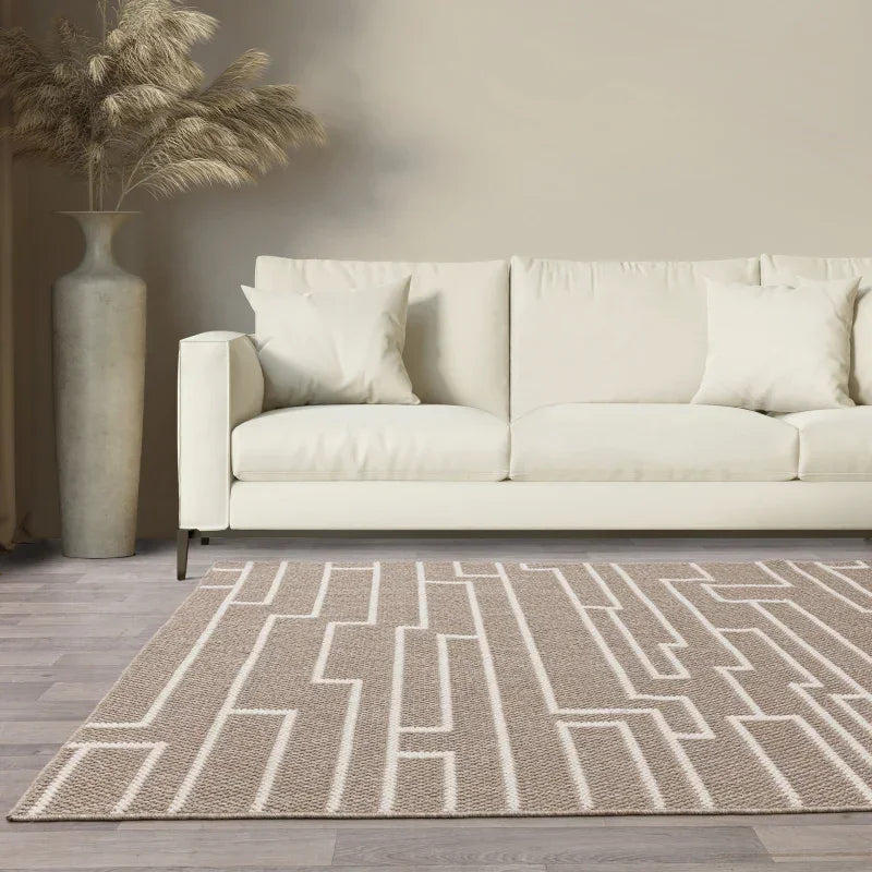 Cream fabric sofa with neutral geometric rug in modern living room with tall vase decor
