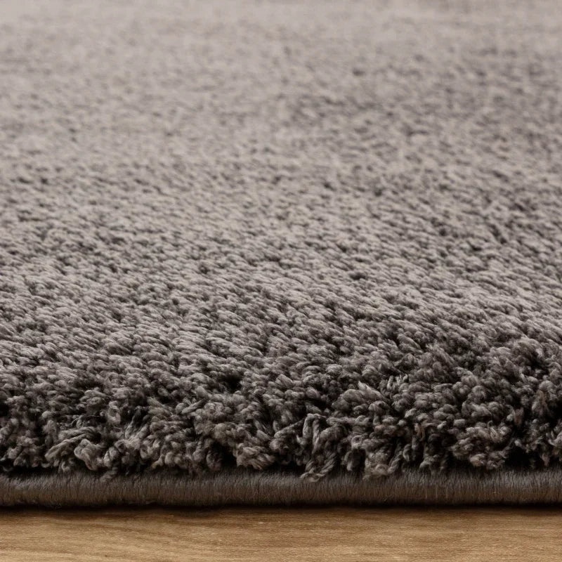 Grey shaggy rug close up showing textured pile and soft fibres on wooden floor