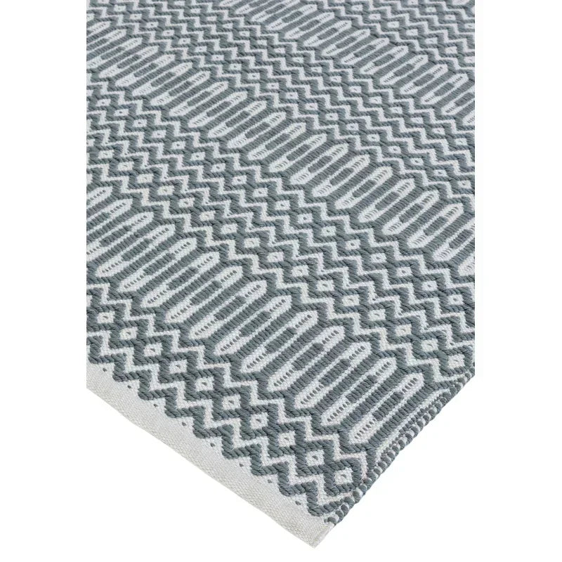 Grey and white patterned rug corner with geometric zigzag and oval designs