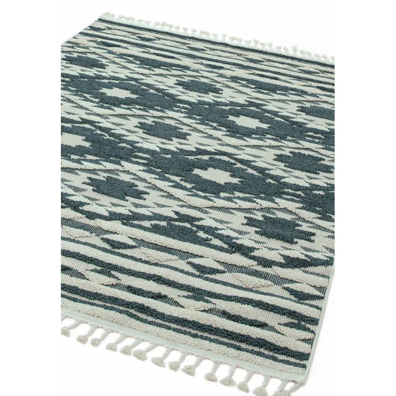 Patterned area rug in blue and cream with fringed edges, shown from an angled view