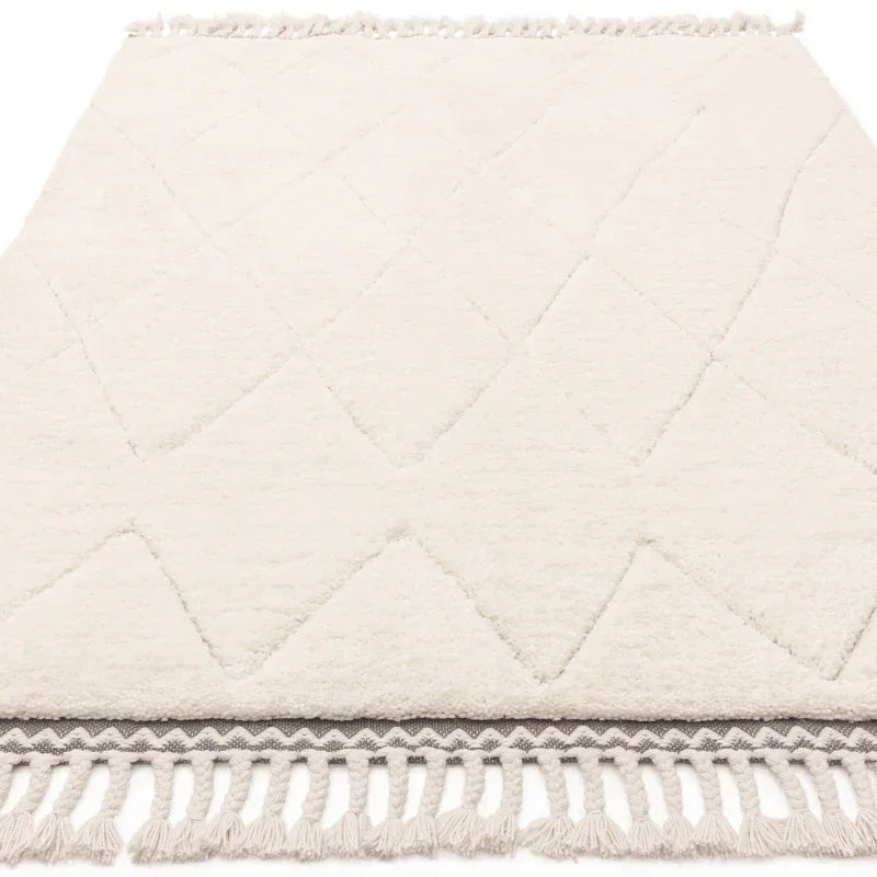 Cream area rug with diamond pattern and tasseled edge on white background