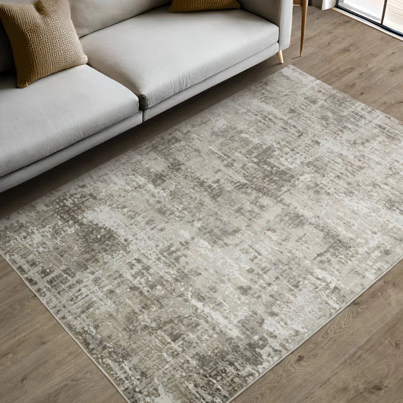 Modern beige and grey area rug on wood floor beside neutral sofa in living room