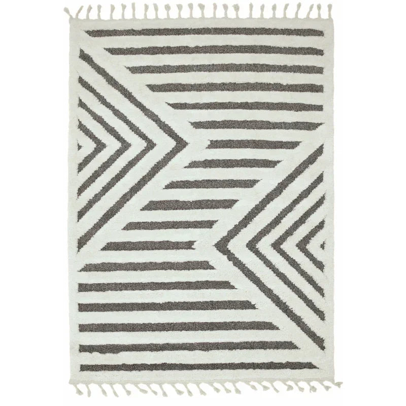 Geometric area rug with black and white chevron stripes and fringe edges