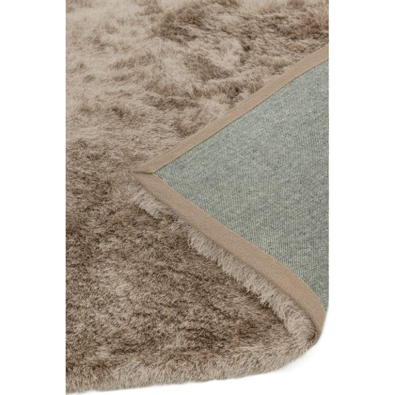 Close-up of beige shaggy rug with soft pile and corner folded to show non-slip backing