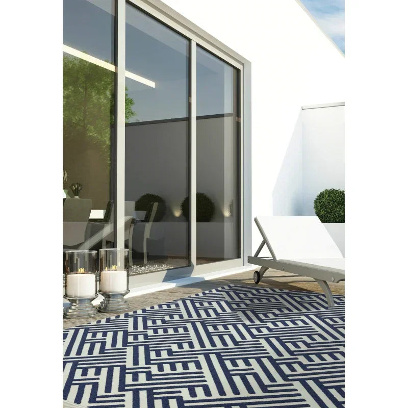 Navy and white geometric outdoor rug on patio with white sun lounger and sliding glass doors