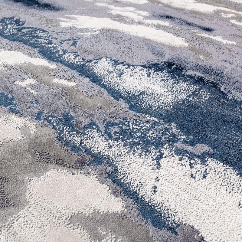 Abstract patterned rug with blue, grey, and cream textured design, close-up view