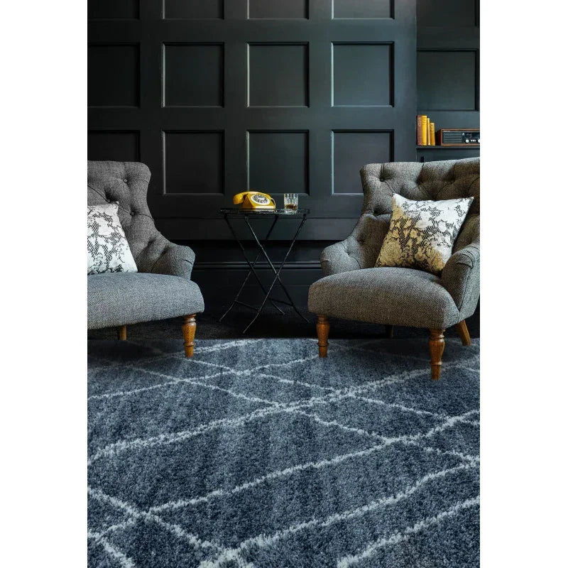 Grey patterned rug with two upholstered armchairs and accent cushions in modern living room