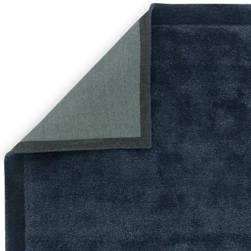 navy blue area rug with corner flipped to show backing texture